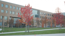 Image displays a UMBC building with trees with red leaves in front.